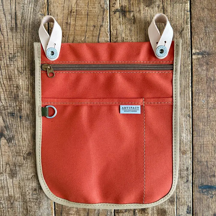 Red /orange pouch with beige accents on a wooden surface