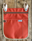 Red /orange pouch with beige accents on a wooden surface