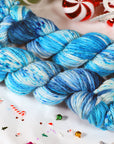 Blue and white yarn skeins on a festive background with candy canes and Christmas decorations.
