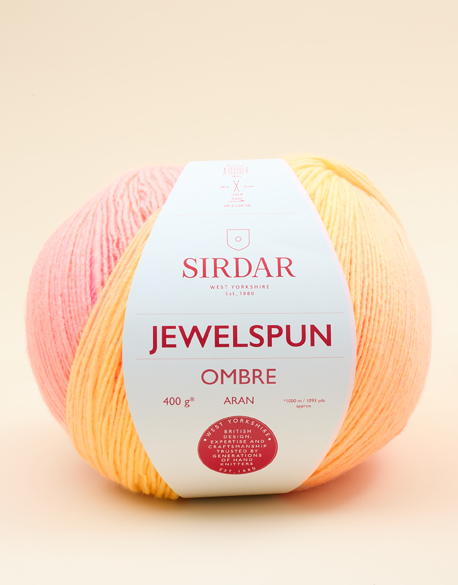 Sirdar Jewelspun Ombre yarn ball with pink and orange gradient on a beige background