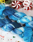 Blue yarn skeins on a festive background with candy canes and peppermints.
