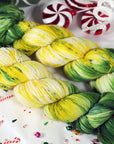 yarn skeins in green, yellow, and white on a festive background with candy canes and Christmas decorations.