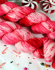 Red and pink yarn skeins on a festive background with candy canes and peppermints.