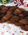 Two skeins of brown yarn on a white background with Christmas-themed decorations.