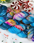 Colorful worsted weight skein of yarn on a decorative background with candy canes