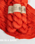 Two skeins of bright tomato red yarn with labels on a white background