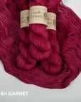 Balls of garnet colored yarn with labels on a white background
