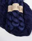 Three skeins of dark blue yarn with labels on a white background