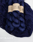Three skeins of dark blue yarn with labels on a white background