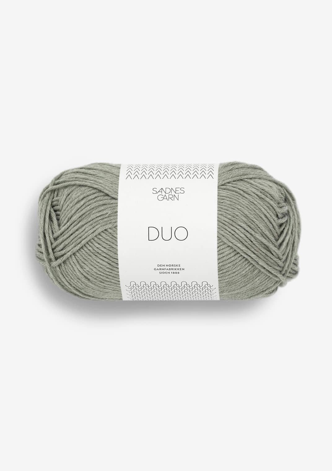 Ball of light sage green yarn with a label on a white background