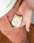 A close up of a young child with a cat pocket hug in his palm ready to slide it into a pants pocket.