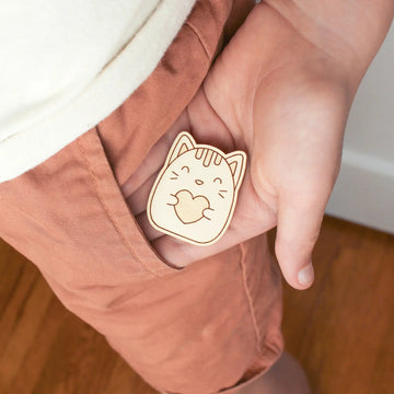 A close up of a young child with a cat pocket hug in his palm ready to slide it into a pants pocket.