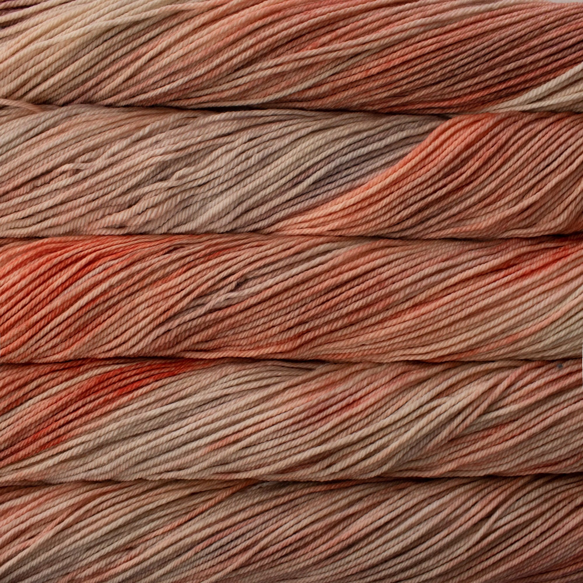 Close-up of multicolored yarn skeins with shades of brown, tan, coral and red.
