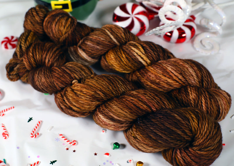 Brown yarn skeins on a festive background with candy canes and Christmas decorations.