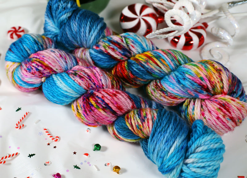 Colorful skeins of yarn on a white surface with candy canes and peppermints.