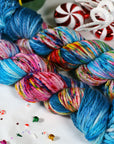 Colorful skeins of yarn on a white surface with candy canes and peppermints.