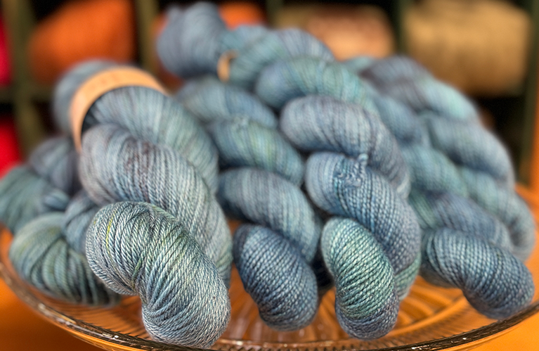 Blue skeins of yarn on a glass plate with a blurred background
