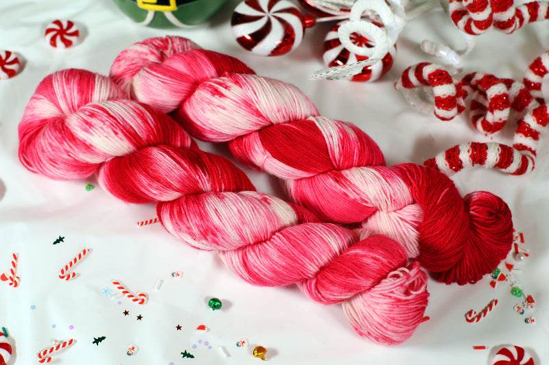 Red and pink yarn skeins on a white background with candy-themed decorations