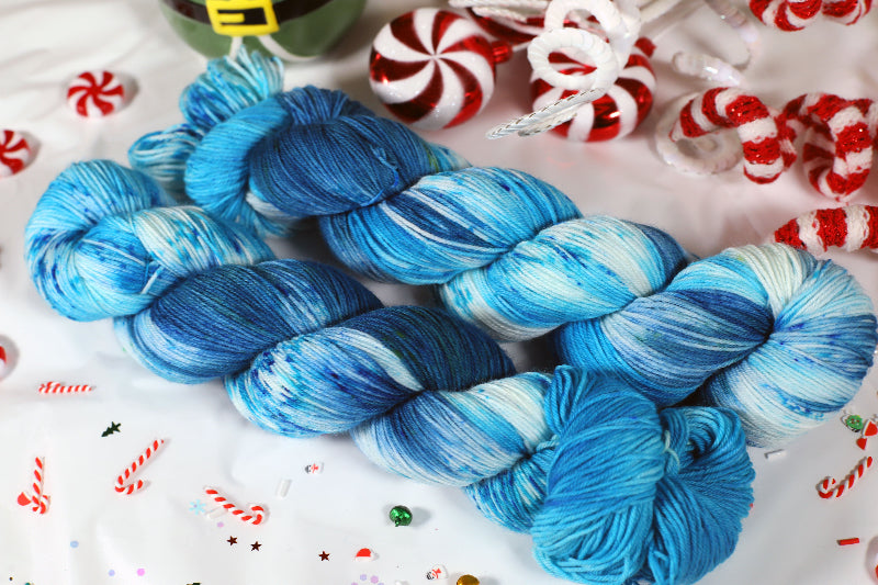 Blue yarn skeins on a festive background with candy canes and peppermints.