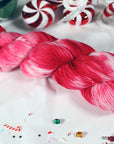 Pink, red and white sparkly yarn skein with Christmas-themed decorations on a white background