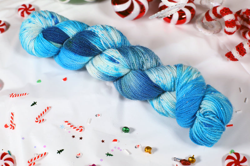 Sparkly Blue and white skein of yarn on a festive background with candy canes and sprinkles.