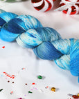 Sparkly Blue and white skein of yarn on a festive background with candy canes and sprinkles.