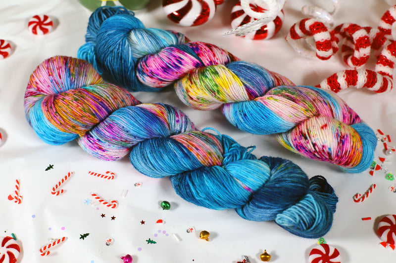 Colorful skeins of yarn on a festive background with candy canes and Christmas decorations.