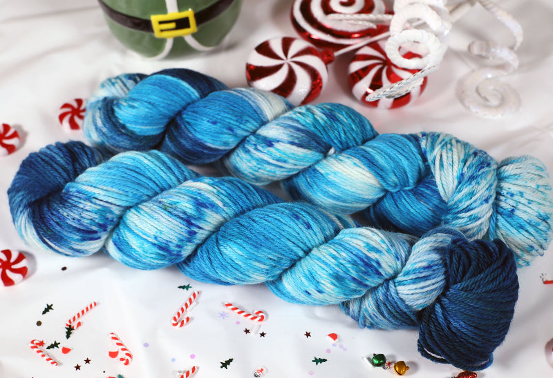 Blue and white skein of yarn on a festive background with candy canes and a gnome figurine.