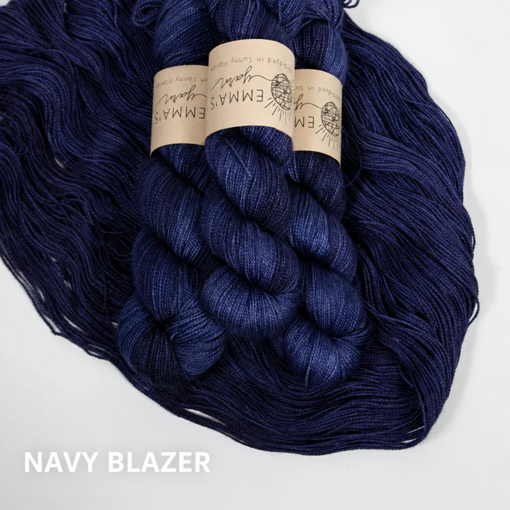 Three skeins of dark blue yarn with labels on a white background